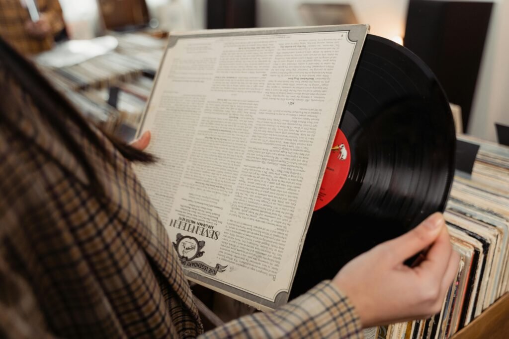 Close-up of a person holding and browsing vinyl records in a nostalgic music store.