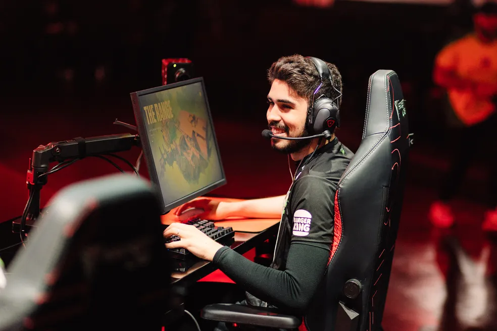 Jogador profissional de eSports competindo em campeonato de FPS competitivo em setup gamer com headset e monitor
